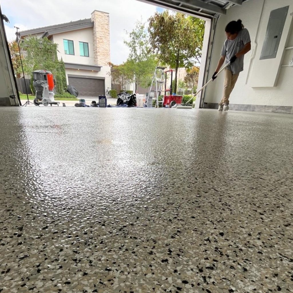 a person installing a grey, black, and white epoxy floor in miami