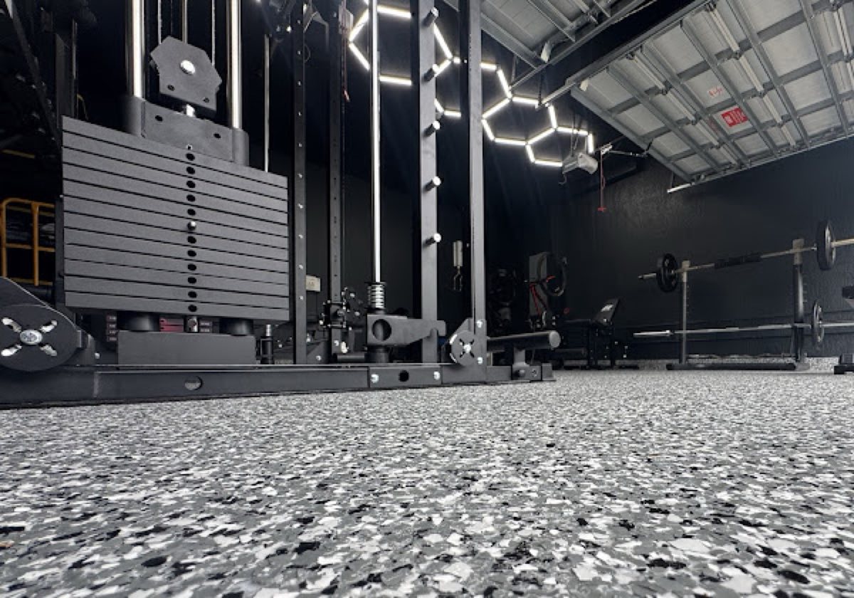 Commercial gym with black and white flake epoxy floor under hex lighting